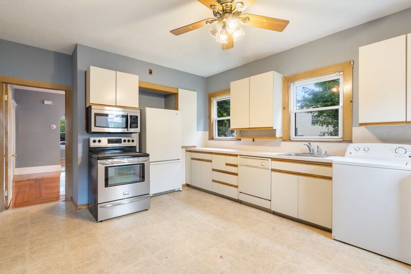 Kitchen with range with microwave hood and refrigerator.  Whit cabinets with wood trim.